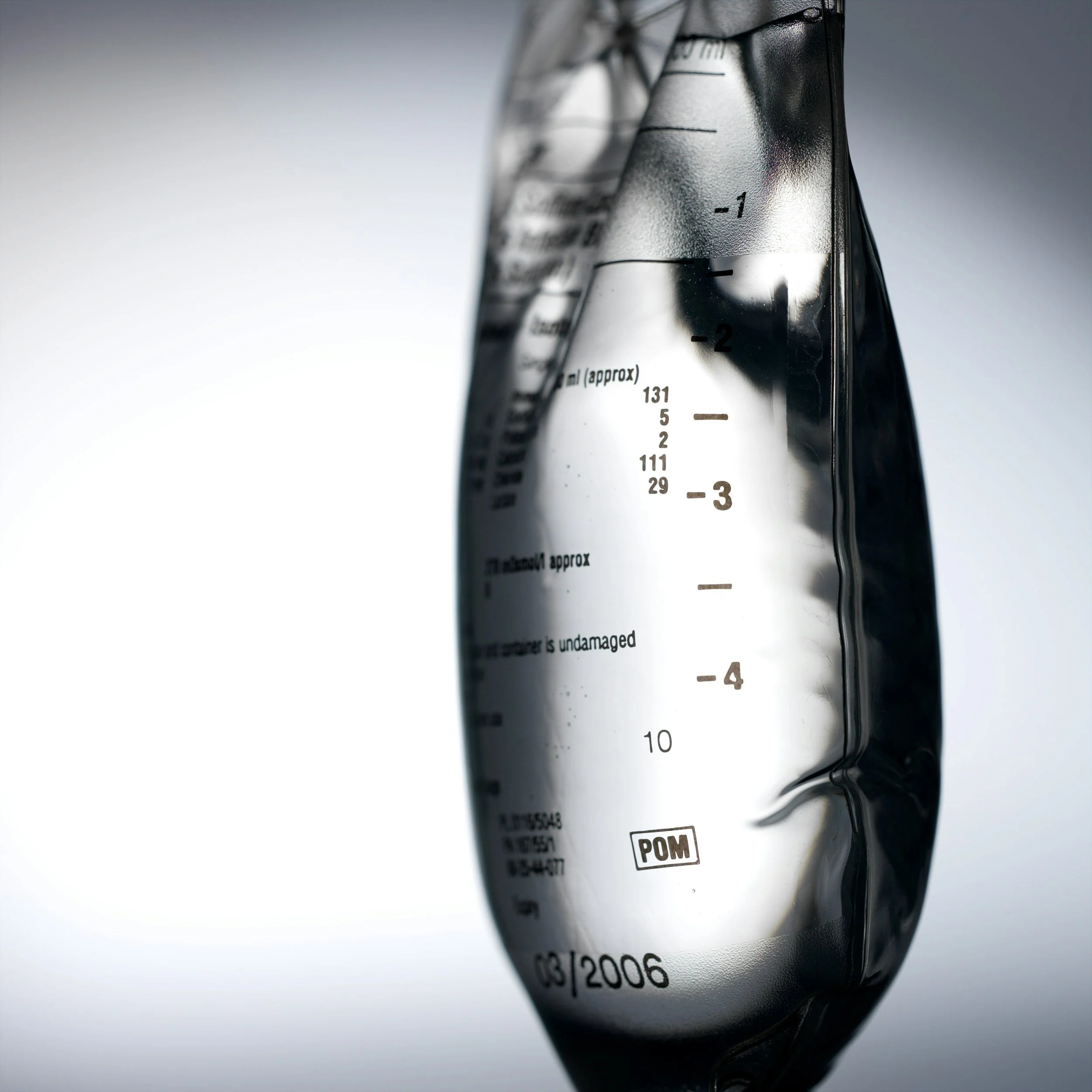 Close-up of a clear, crumpled plastic measuring cup with measurement markings in milliliters on a white background.