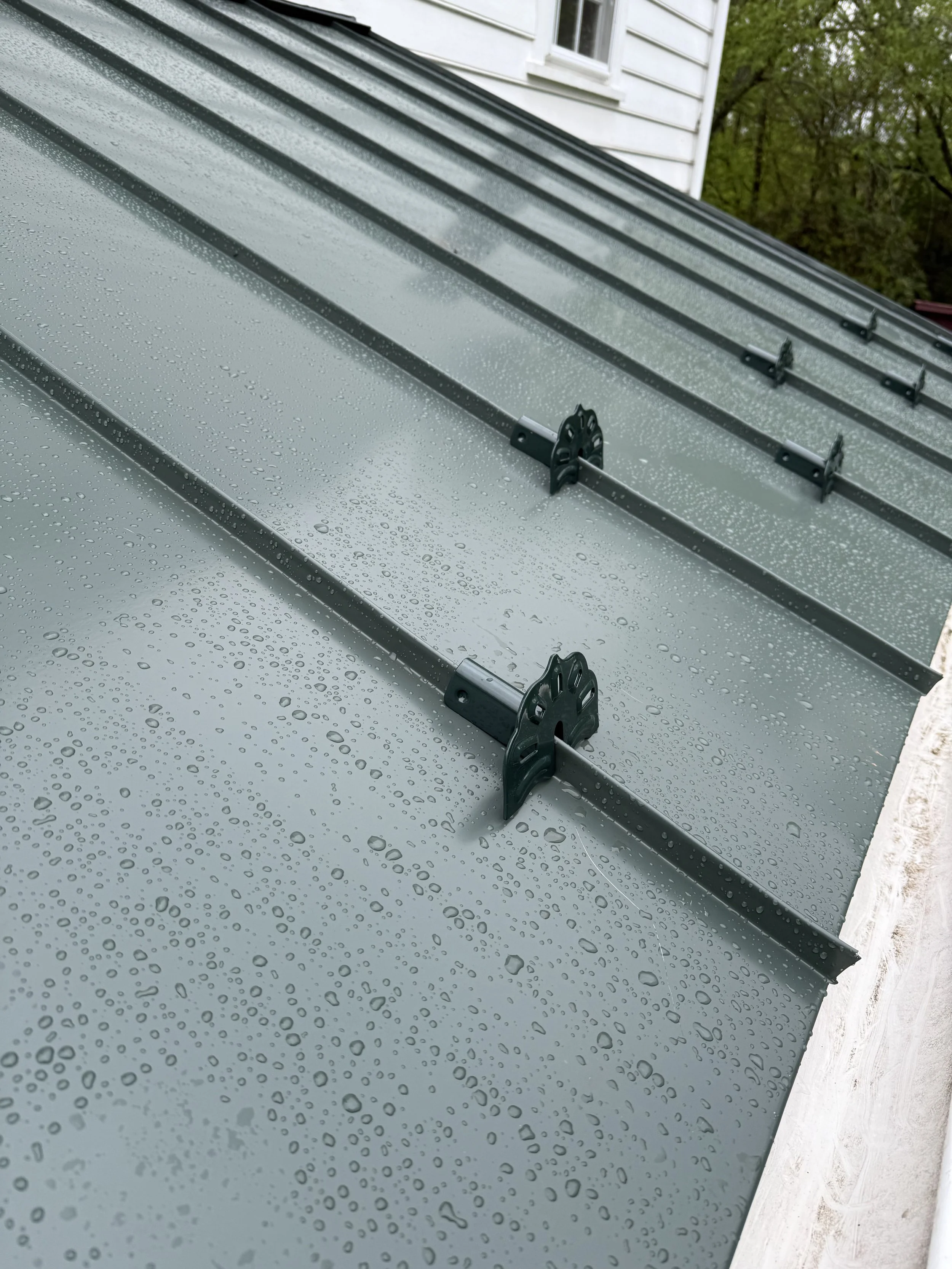 Metal roof with mounting brackets, part of a green metal roofing system.