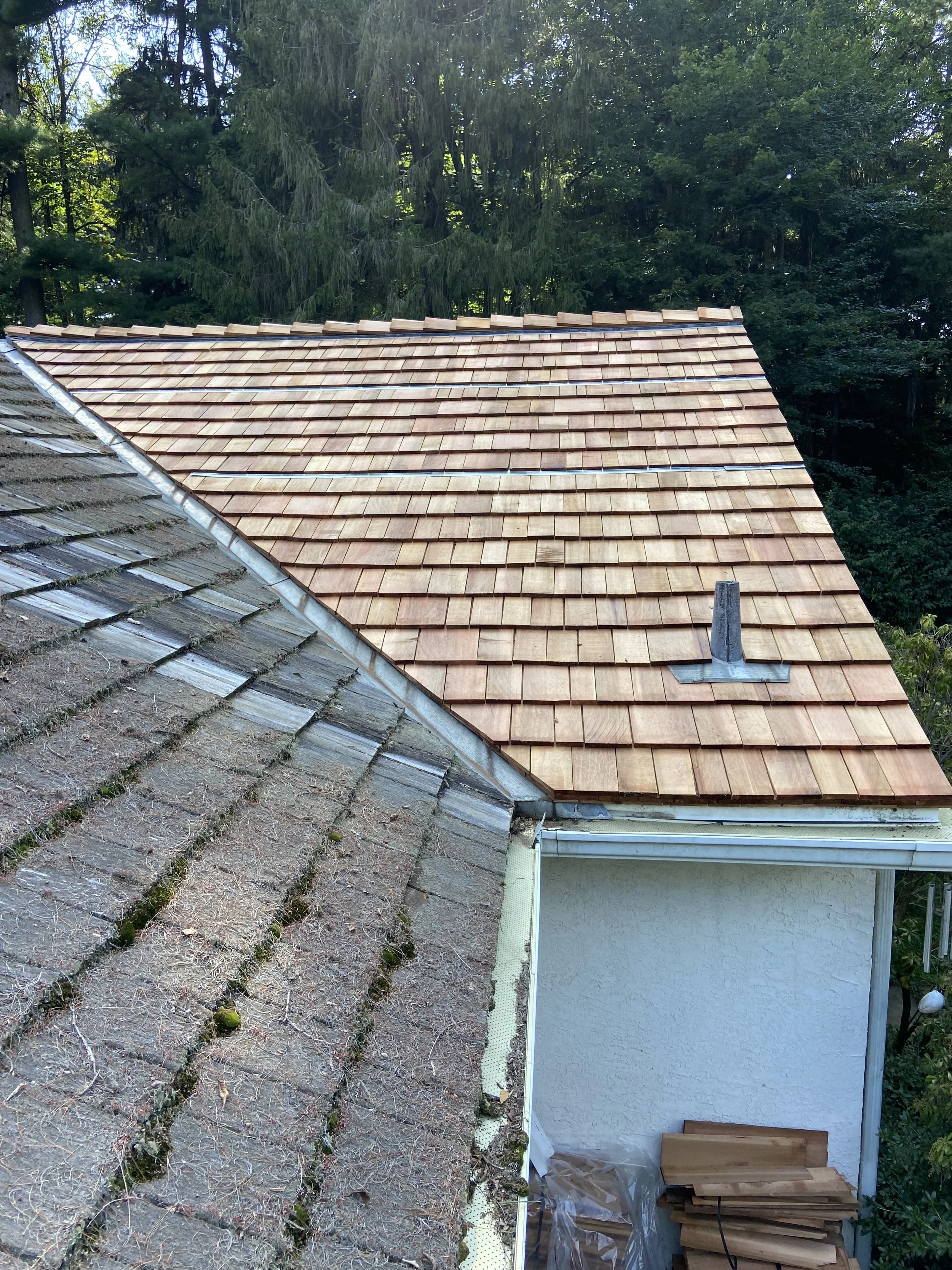 New cedar shake roof installation showcasing a durable, weather-resistant, and aesthetically pleasing upgrade compared to an old, moss-covered, deteriorating roof. Improve curb appeal and protect your home with expert roofing services.