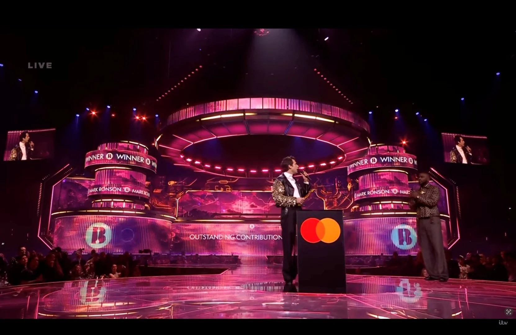 Picture of presenters on stage rewarding the winner