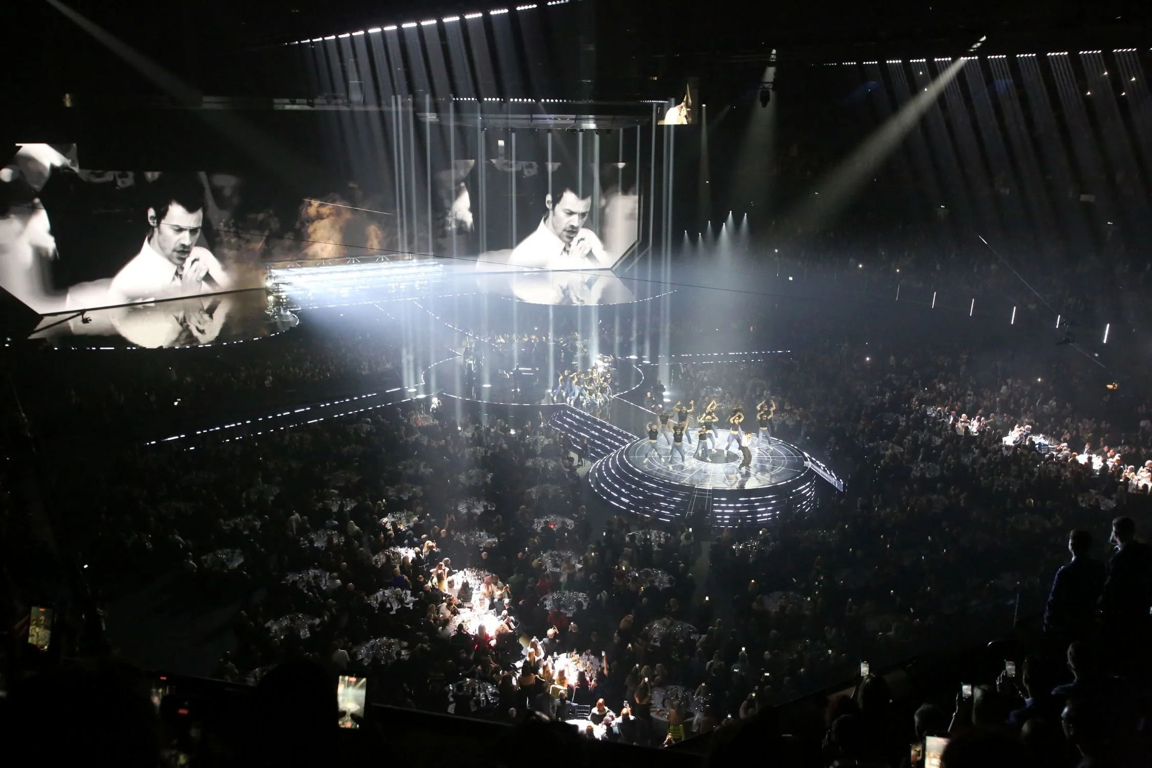 singer on circular stage performing opening act beams of lights on second stage from the spaceship above it