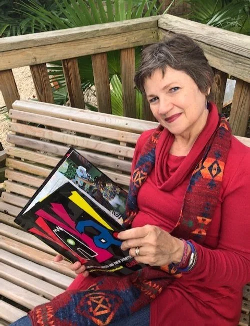 Claudia Barker, a woman with short gray hair sitting on a wooden bench outdoors in New Orleans, holding her first book and smiling.