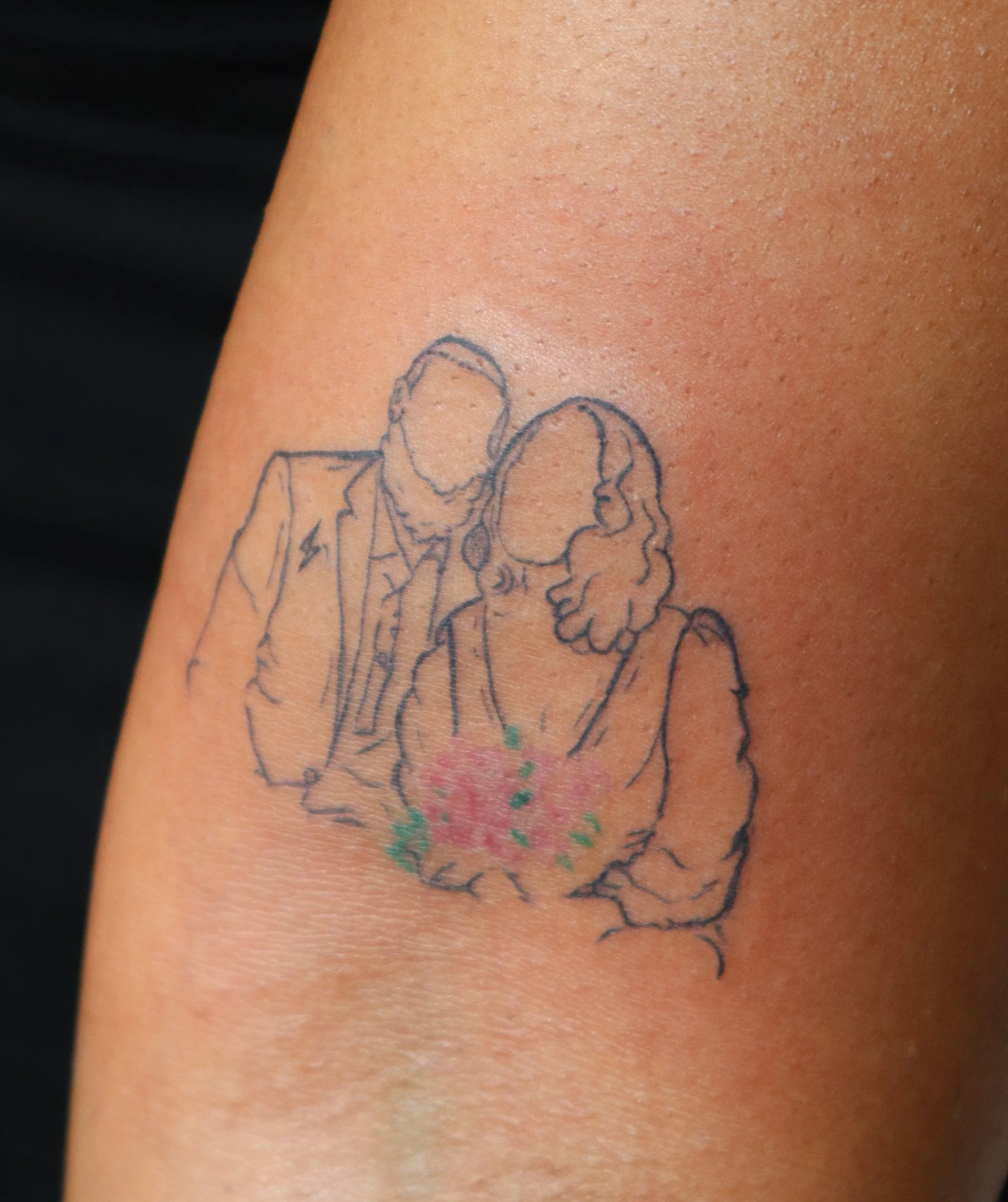 Tattoo of a man and woman with faceless outlines, with the woman holding flowers