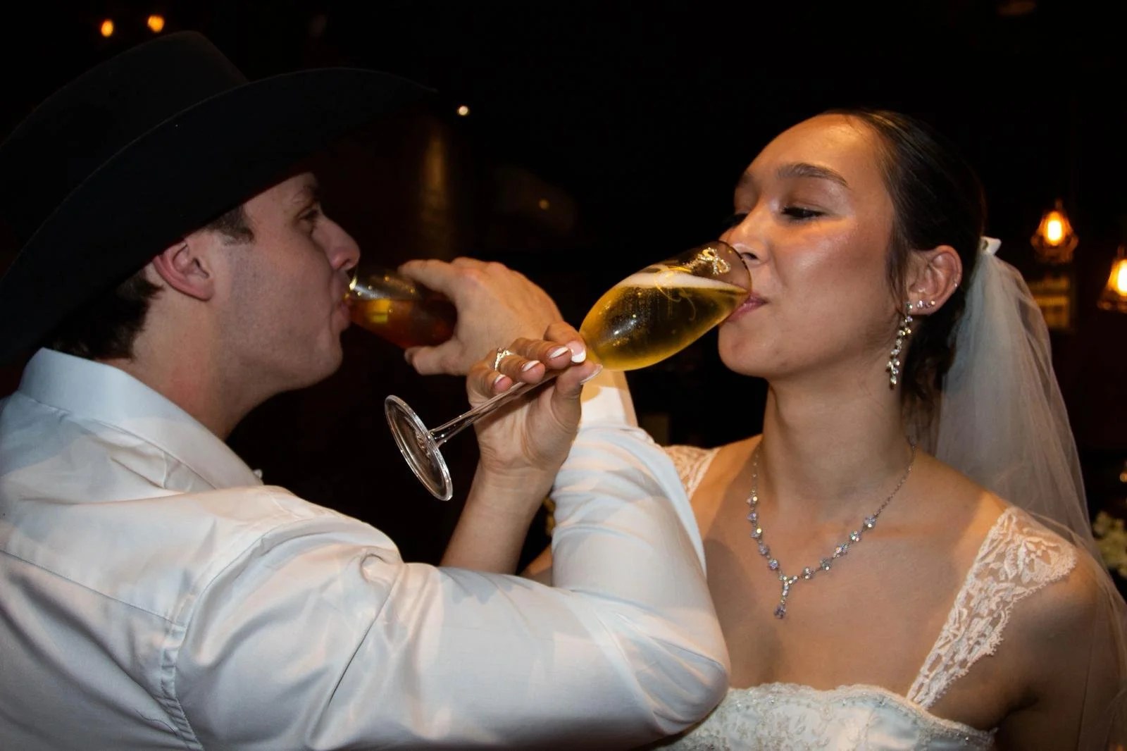 bride and groom with arms linked drinking champagne