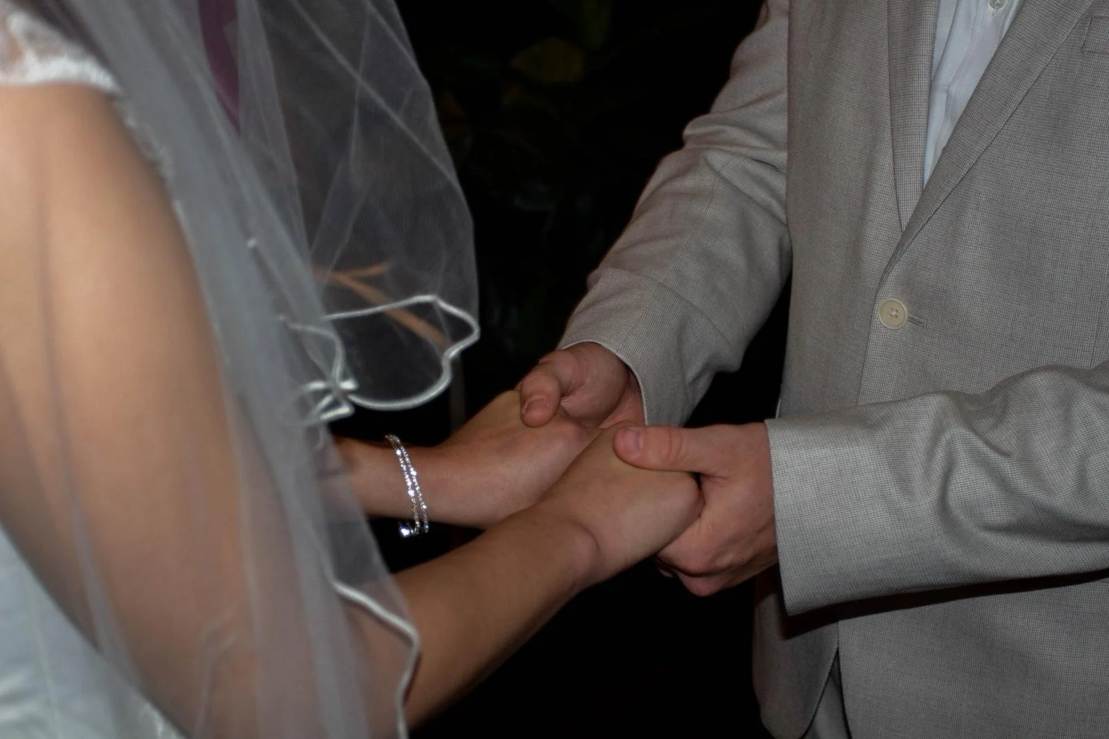hands of bride and groom in ceremony black and white
