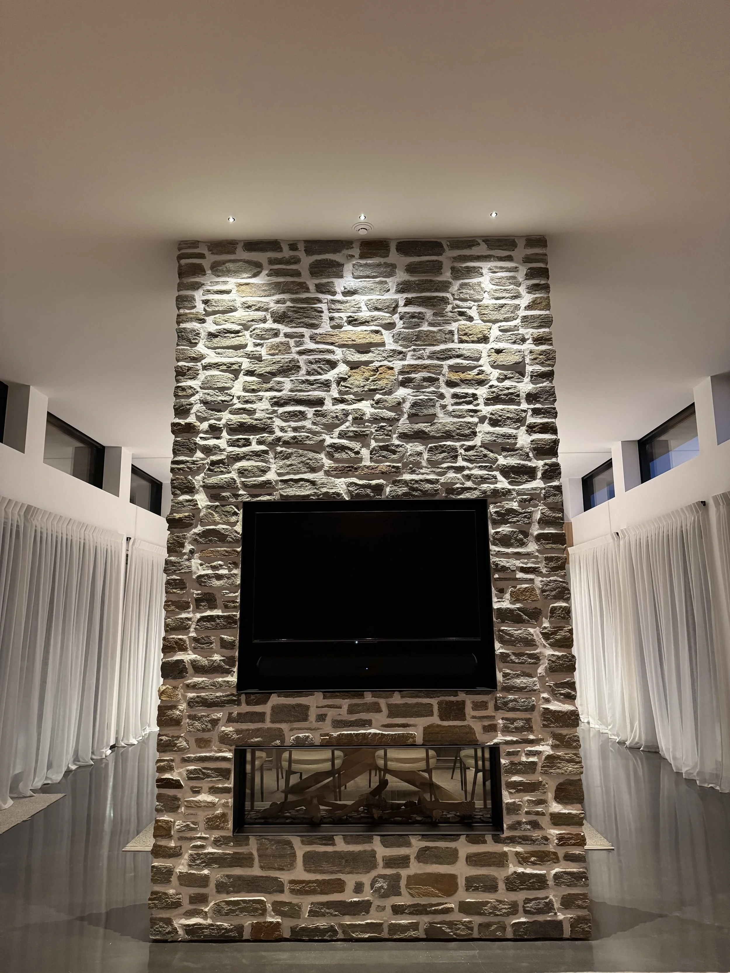 Stone full hight wall with with TV and fire, pin lights washing down wall 