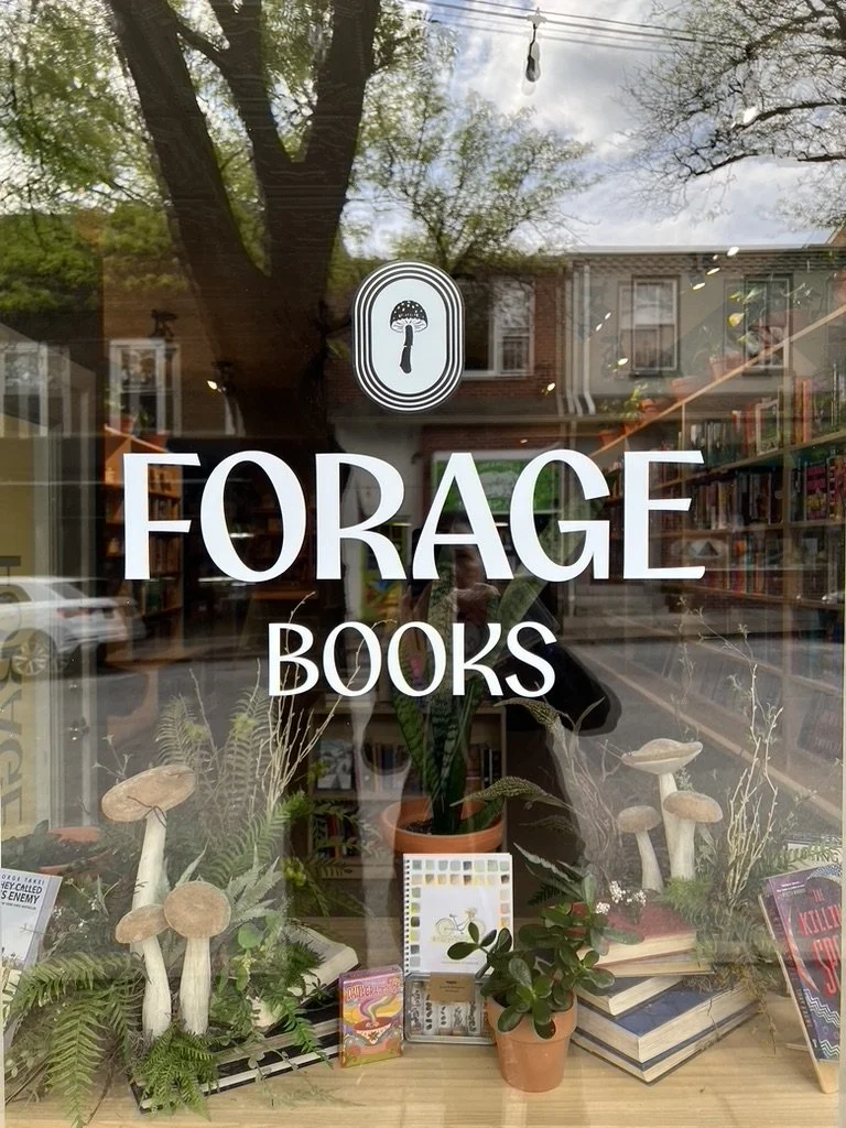 Mushroom-themed window display at Forage Books with the name and logo of the store on the glass