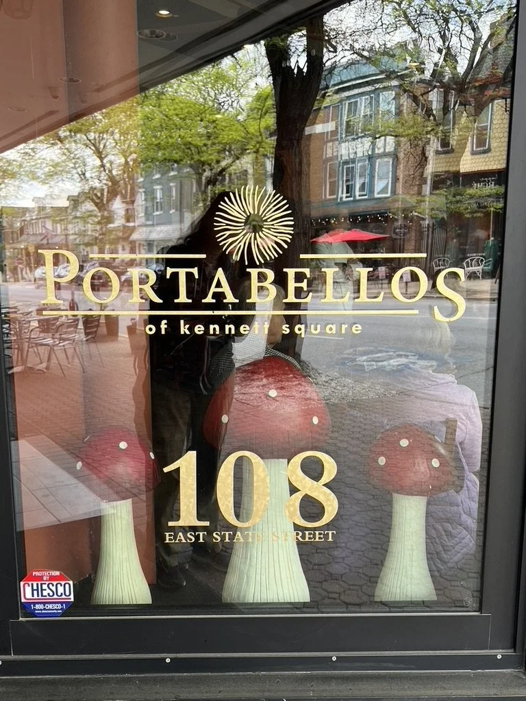 Mushroom-themed window display at Portobello's of Kennett Square with the name and logo of the restaurant on the glass