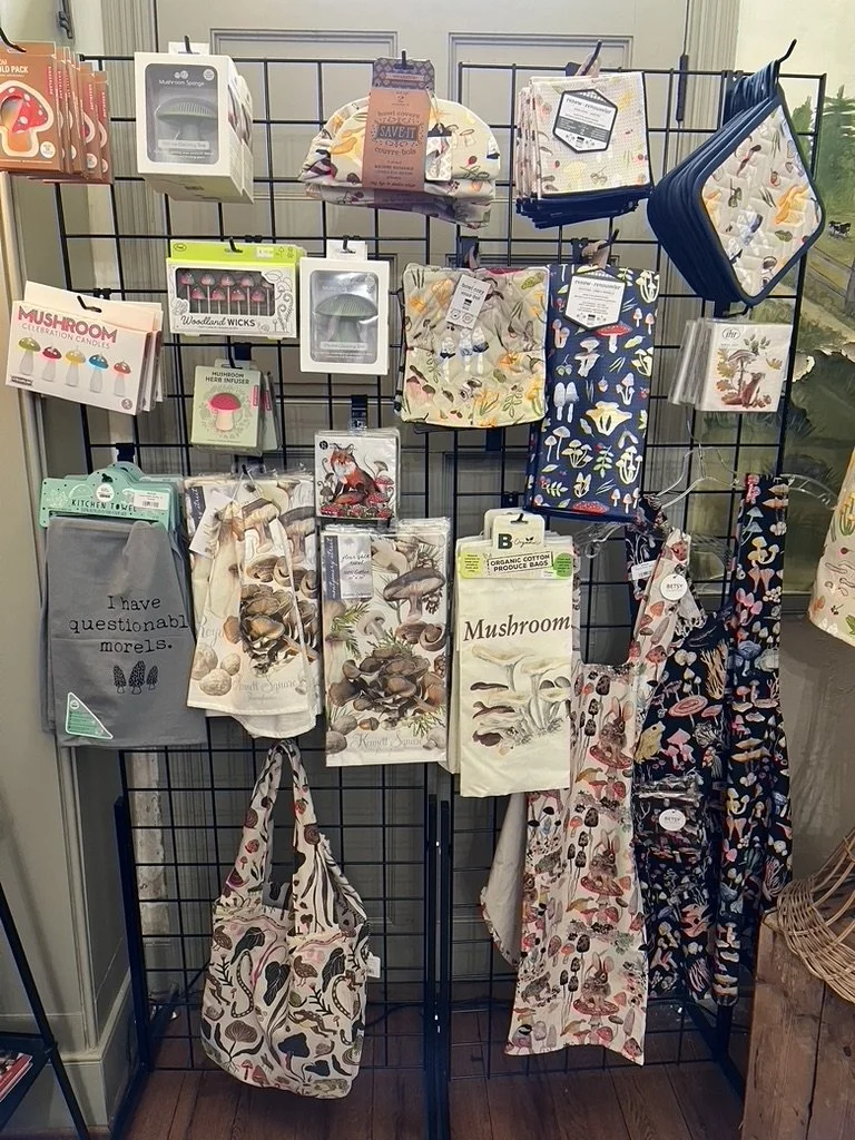 Display filled with mushroom-themed kitchen items, such as towels, aprons, and pot holders.