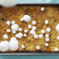 Mini marshmallows falling down onto a sheet pan cake.