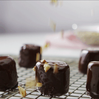 Crushed pecans falling onto a chocolate covered marshmallow.