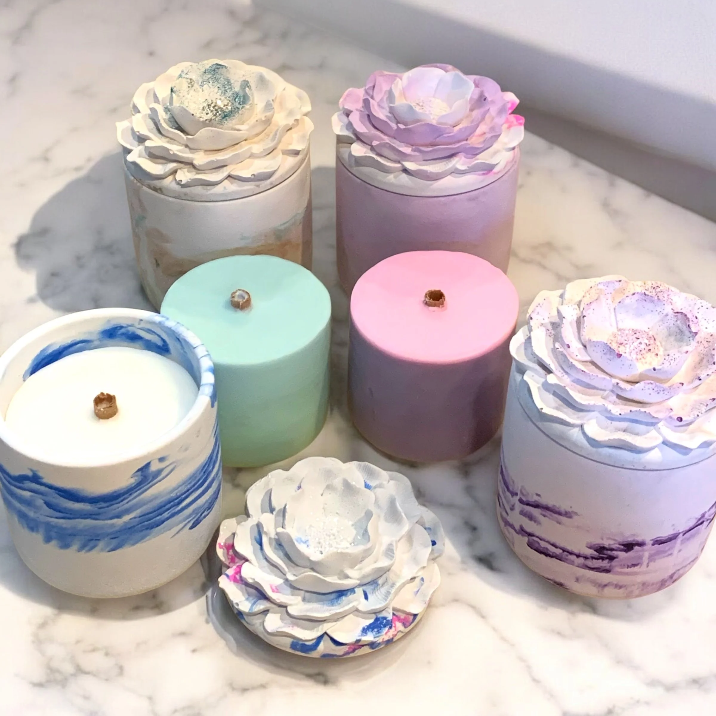 A Collection of the Mothers Day Bundle Refillable Candle Jars with wax refills, arranged on a marble surface.