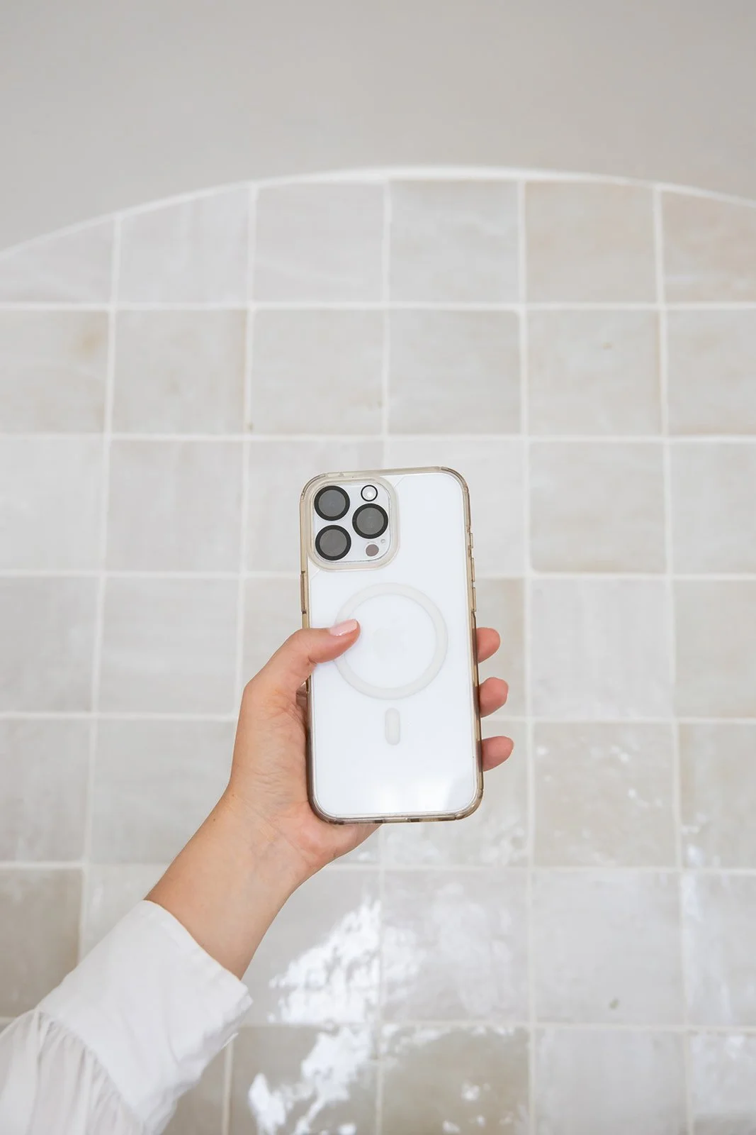 A person holding an iPhone with a pop socket against a tiled floor.
