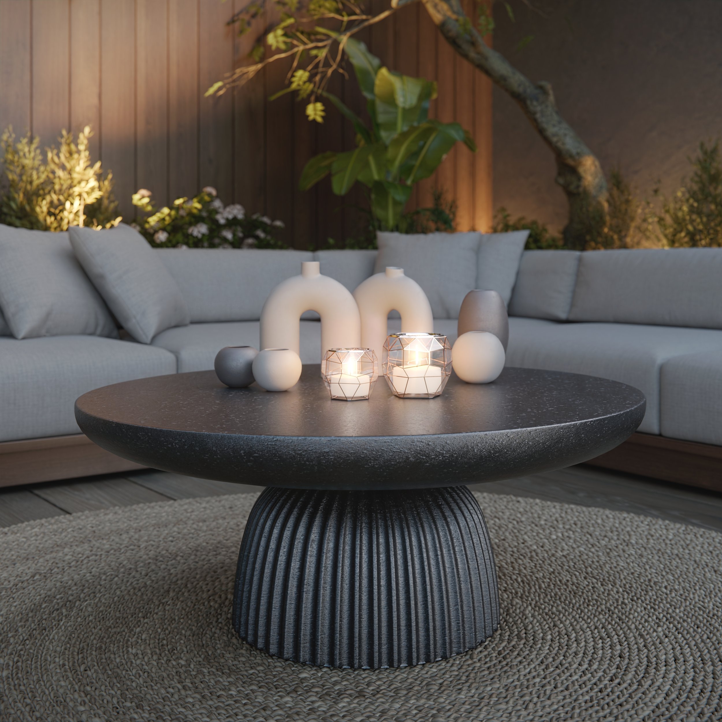 Closeup of a round coffee table with a textured, fluted base and a smooth, dark tabletop