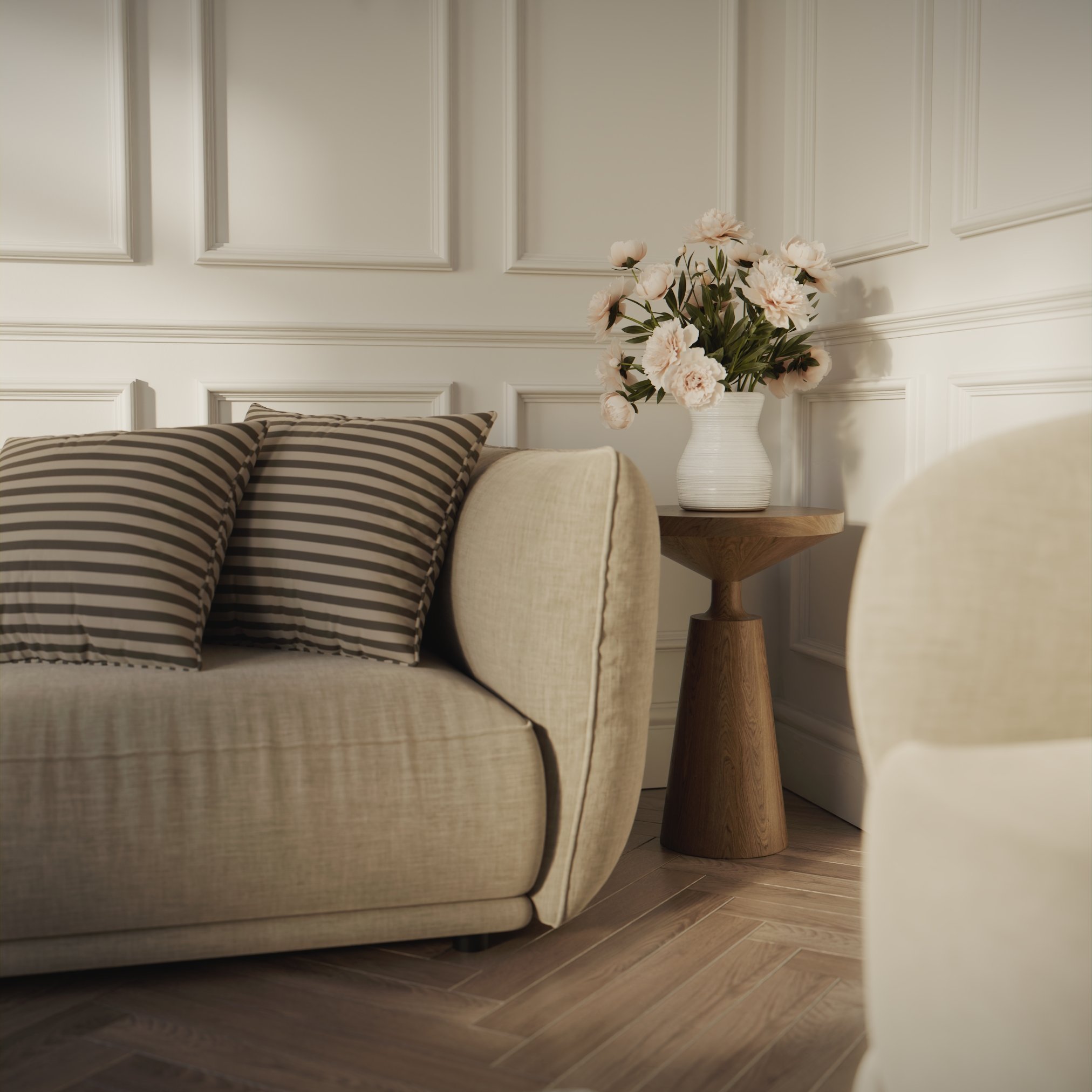 View of a corner where we can see the armrest of a sofa and an end table with a vase with roses
