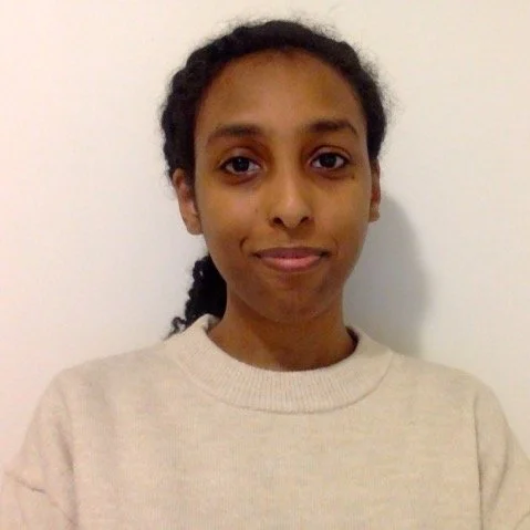 Photo of young Black woman wearing beige sweater miling at camera