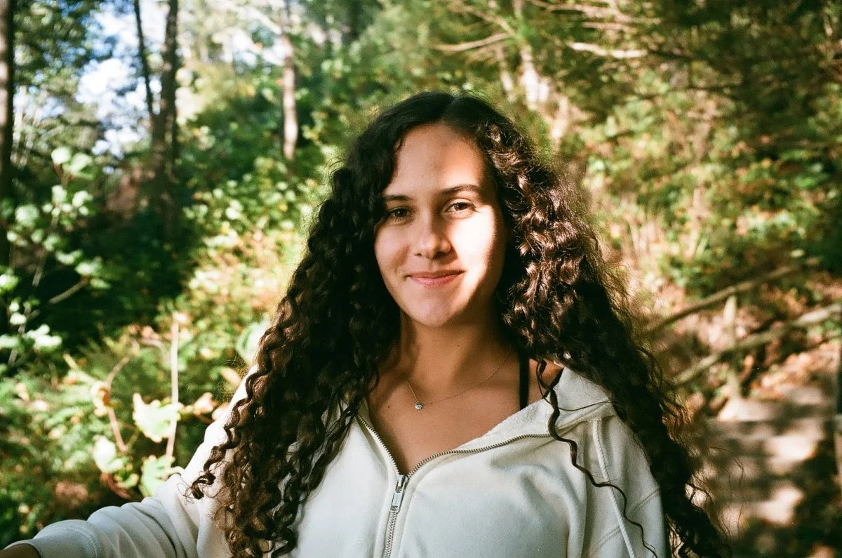 Anjali Carter-Rau, in a white hoodie, pictured in a forest