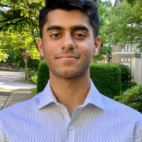 Sameer smiling in park with walkway in background
