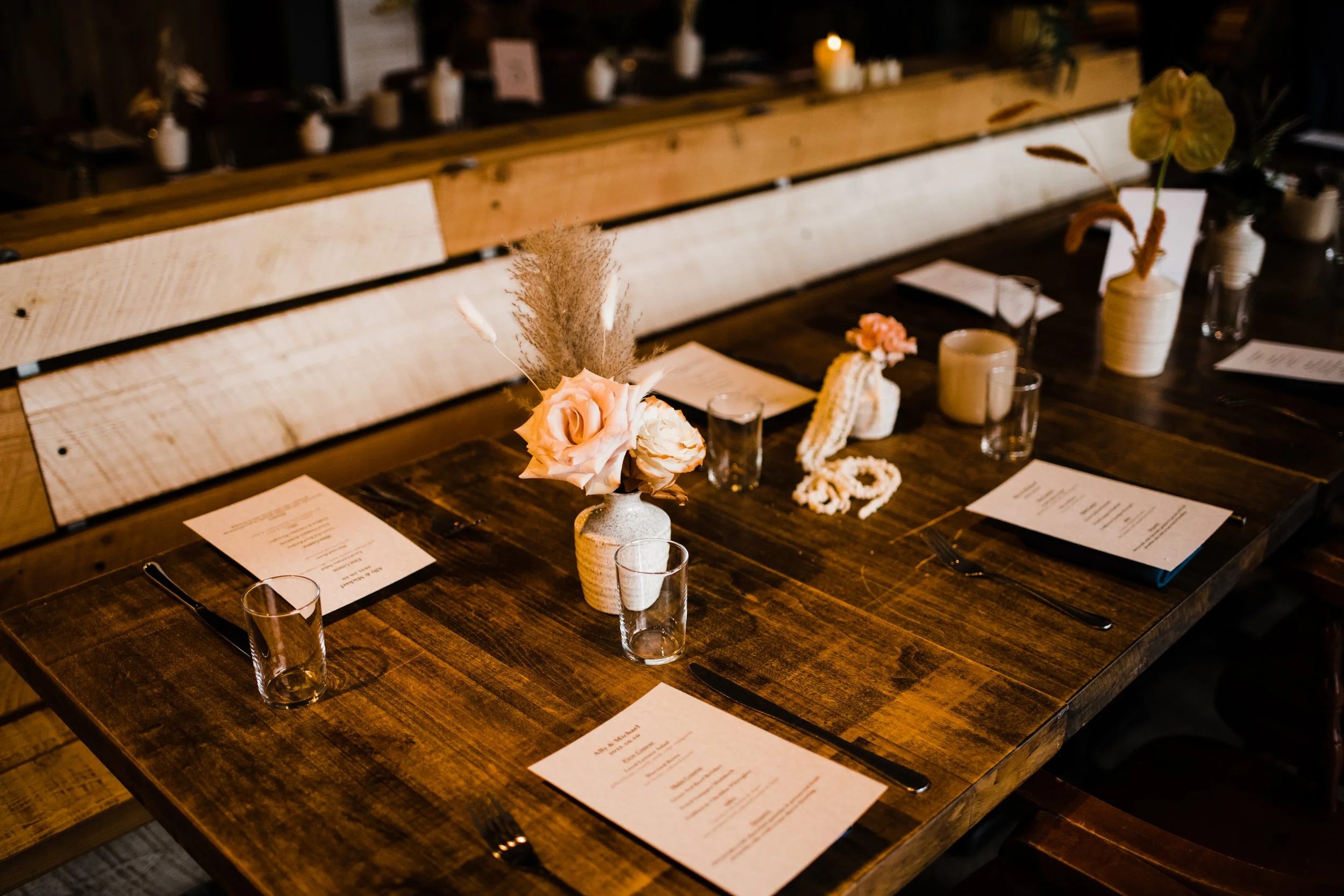 wooden dining table vases with light pink and peach flowers