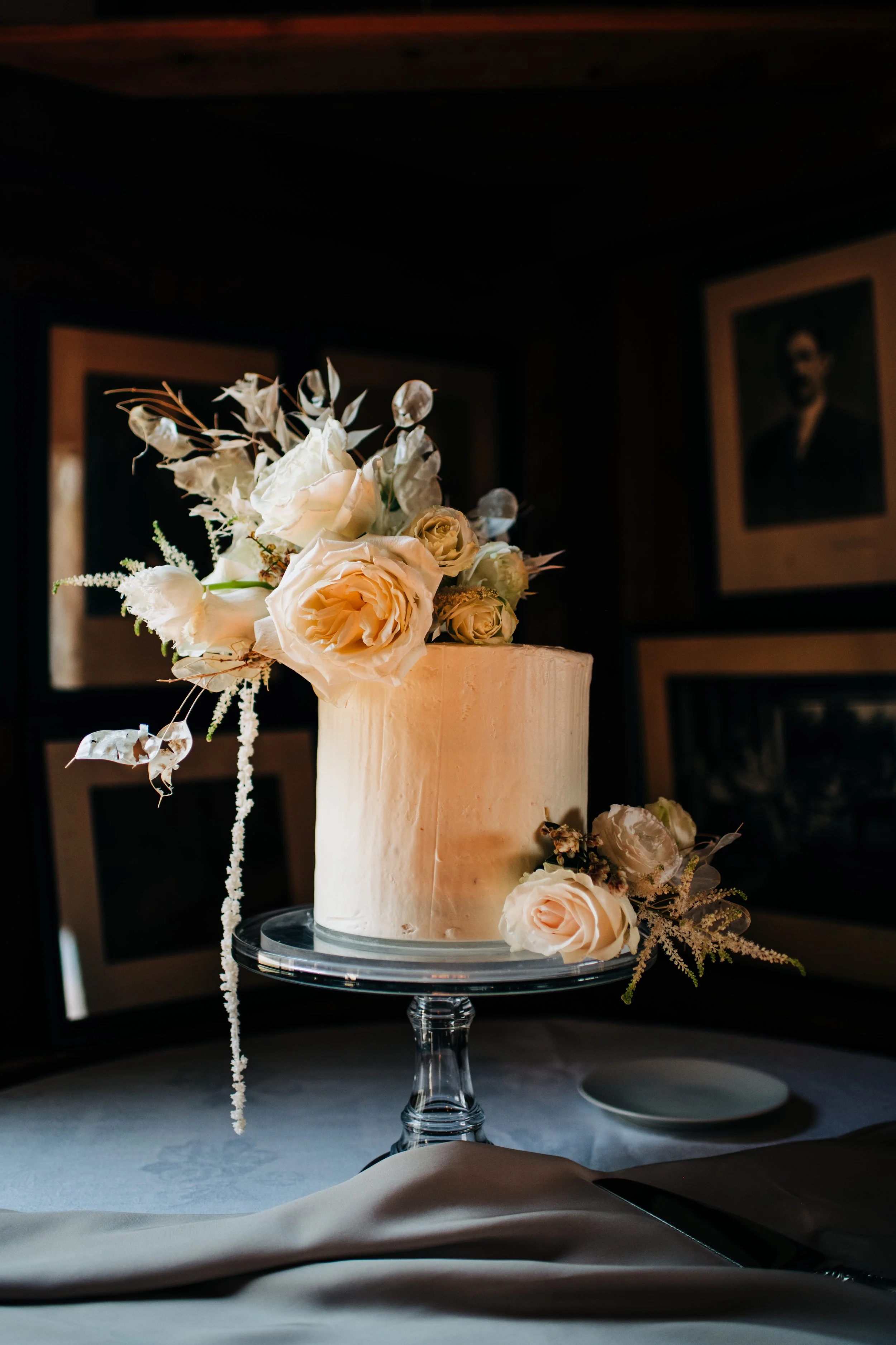 single-tier white wedding cake decorated with cream-colored roses and flowers on top