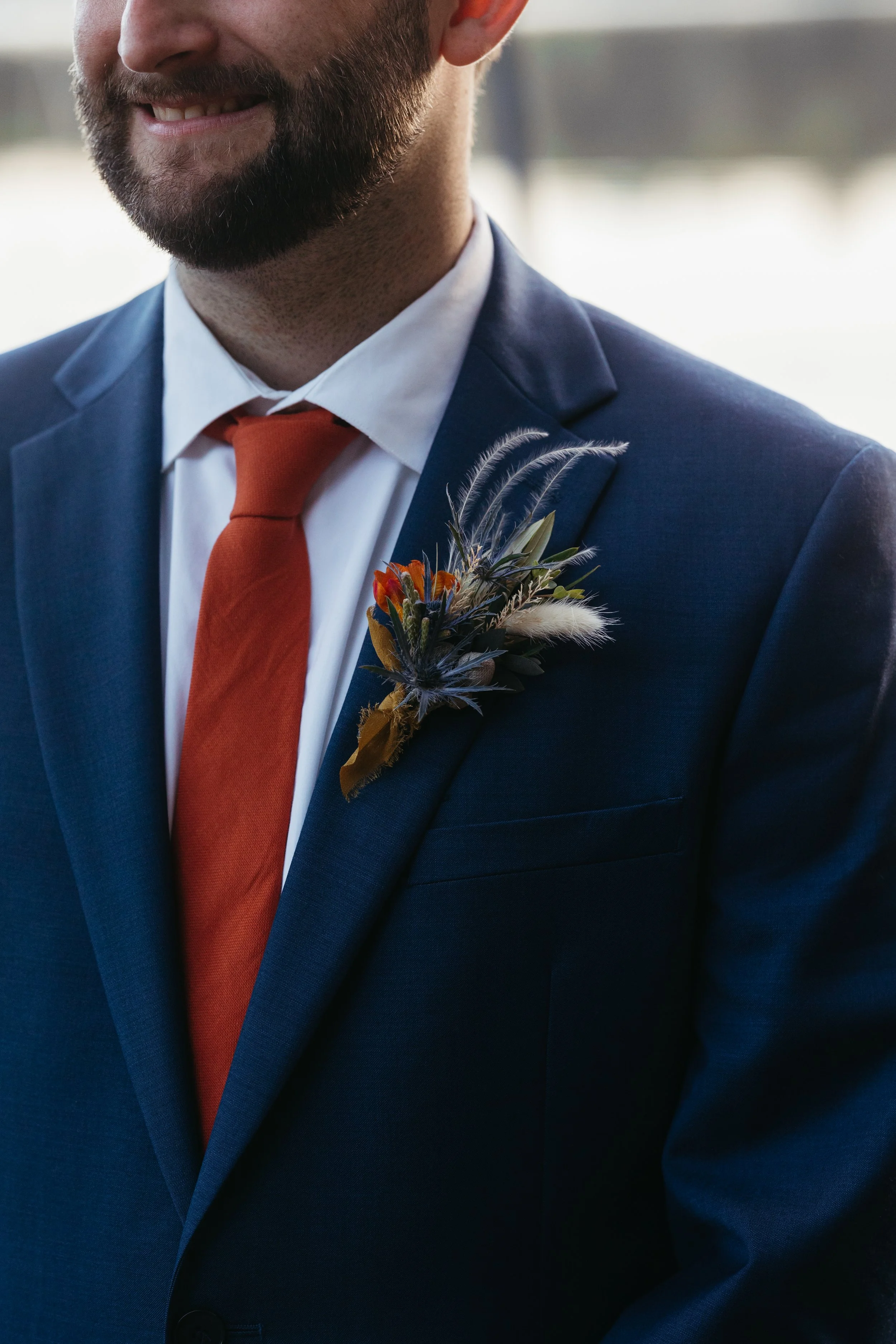 navy blue suit with orange tie, boutonniere