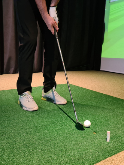 Person preparing to hit a golf ball on an indoor putting green.