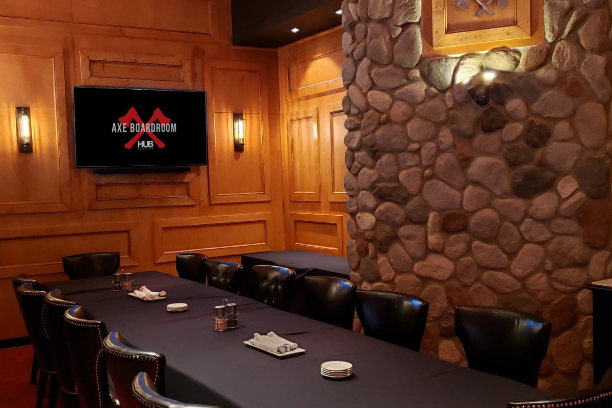 Cozy boardroom with fireplace, stone wall, large table, chairs, and screen.