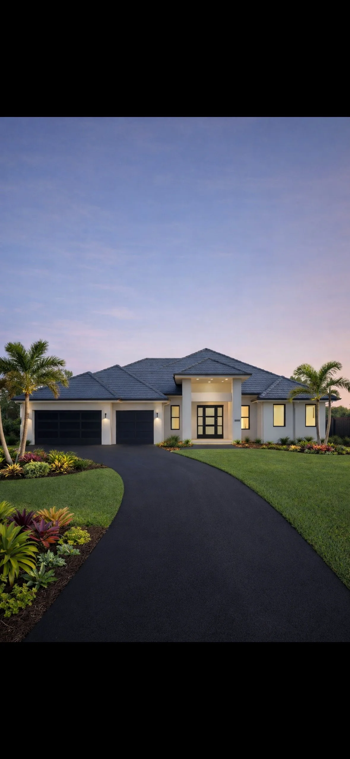 Modern single-story house with a dark driveway, green lawn, palm trees, and minimal landscaping under a twilight sky.