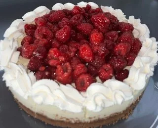 Classic cheesecake topped with fresh strawberries and white whipped cream.
