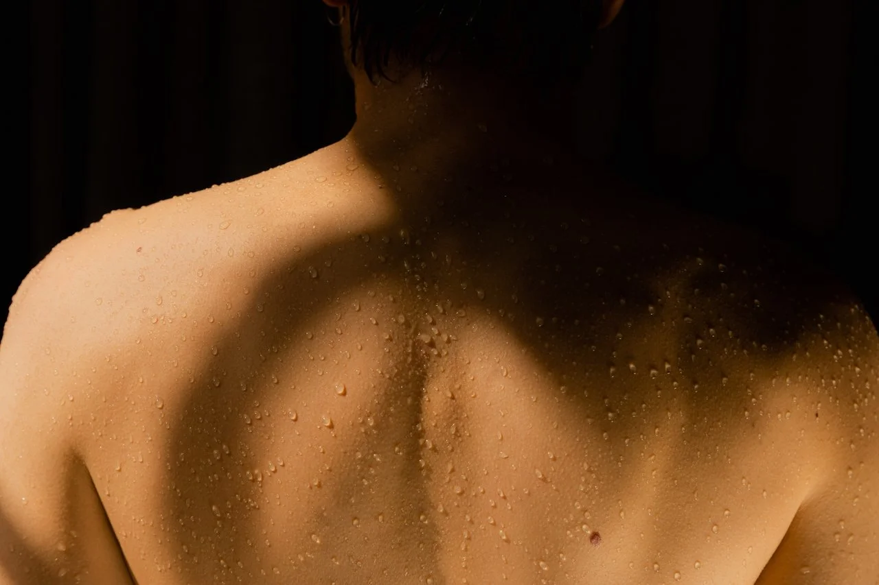 A woman wearing a white strapless top and earphones at the beach.