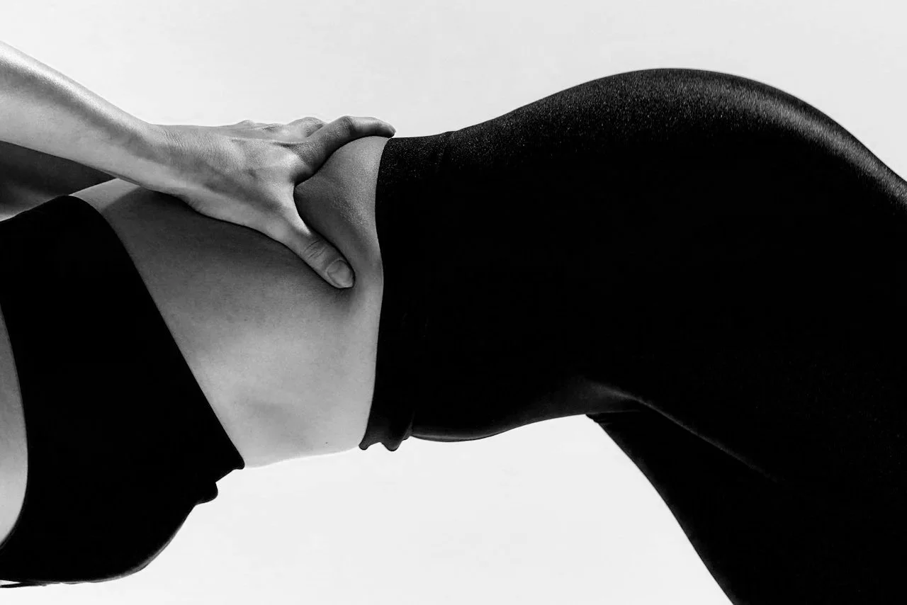 Black-and-white photo of a person demonstrating a side-lying Pilates pose, showcasing controlled form and alignment.