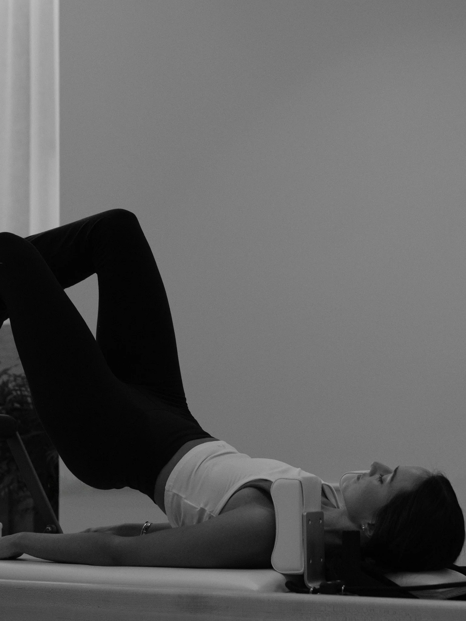 Woman lying on a medical examination table with her legs elevated and feet on the surface, receiving an ultrasound.
