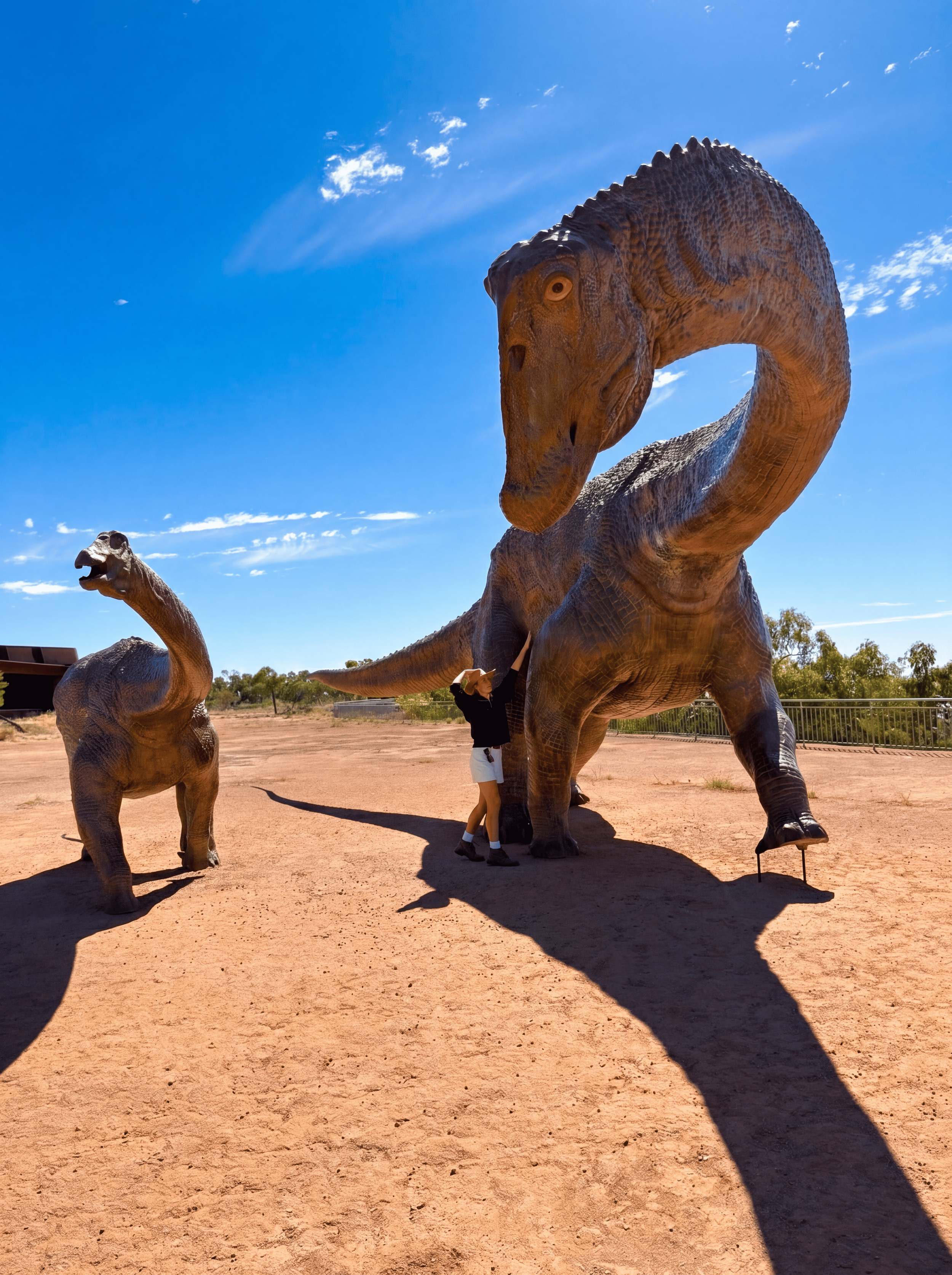 Person and life size dinosaur statue.
