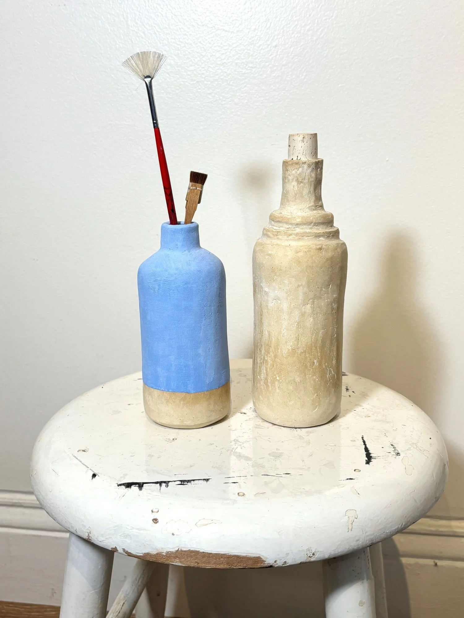 TRASH TO TREASURE VESSELS blue: 6h x 2.5d in. natural: 8h x 2.5d in. upcycled mouthwash and cleaner bottle, paper mâché, joint compound, glue and dry pigment