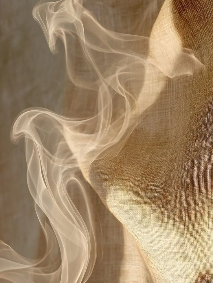 Close-up of wisps of smoke rising next to a piece of textured, beige fabric.