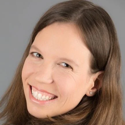 Lächelnde Frau mit braunen Haaren und grauem Hintergrund