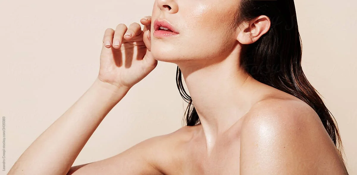 Mujer con piel radiante y cabello oscuro, tocándose la cara.