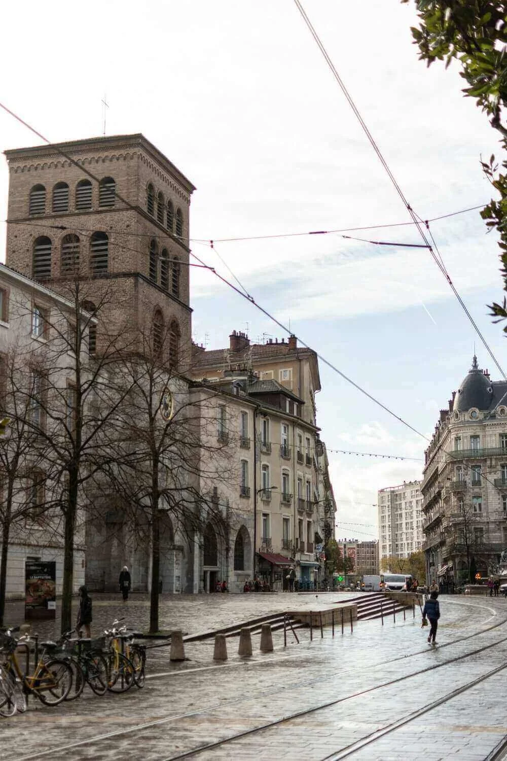 Vue de l’église Saint-André à Grenoble, avec son clocher imposant et un environnement urbain moderne. Idéal pour découvrir comment devenir mannequin d’essayage à Grenoble, une ville où l’histoire et la modernité coexistent harmonieusement.