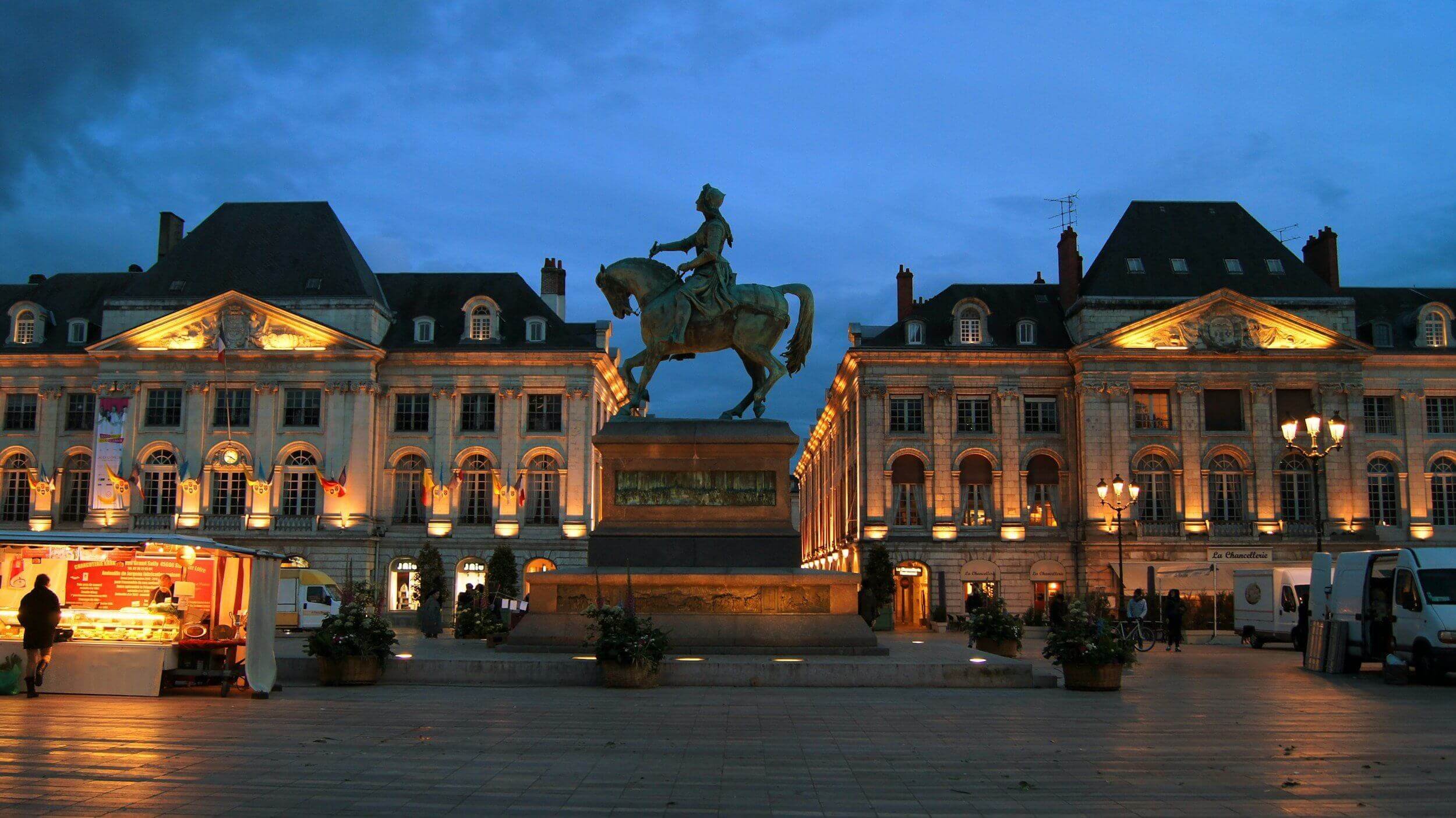 Vue nocturne d’Orléans, avec la Place Reine-Marguerite illuminée et une statue équestre au centre. Idéal pour découvrir notre agence et ses services d’essayage dans cette ville historique et accueillante.