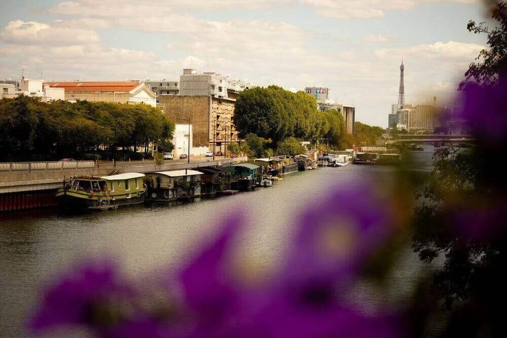 Vue du quai animé de Boulogne-Billancourt, avec des bateaux sur la Seine. En arrière-plan, un mélange harmonieux entre nature et architecture moderne. Idéal pour découvrir comment devenir mannequin d’essayage à Boulogne-Billancourt.