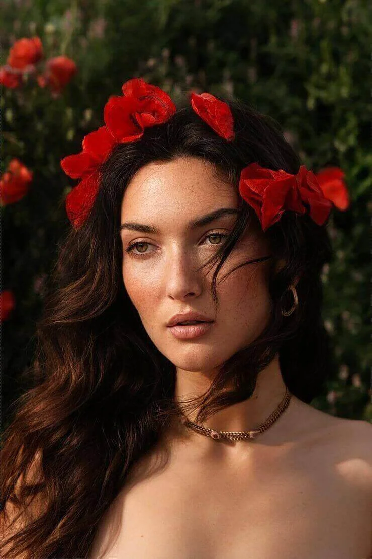 Cette photo montre une modèle portant une couronne de fleurs rouges dans un cadre naturel, symbolisant les services de création de looks proposés par The Casting Fit. L’image met en avant la beauté et la sophistication de nos prestations.