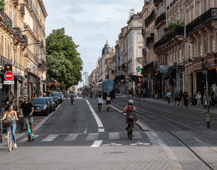Vue d’une rue piétonne animée à Bordeaux, bordée de bâtiments historiques et de vélos en mouvement. Idéal pour découvrir comment devenir mannequin d’essayage dans cette ville accueillante et moderne.