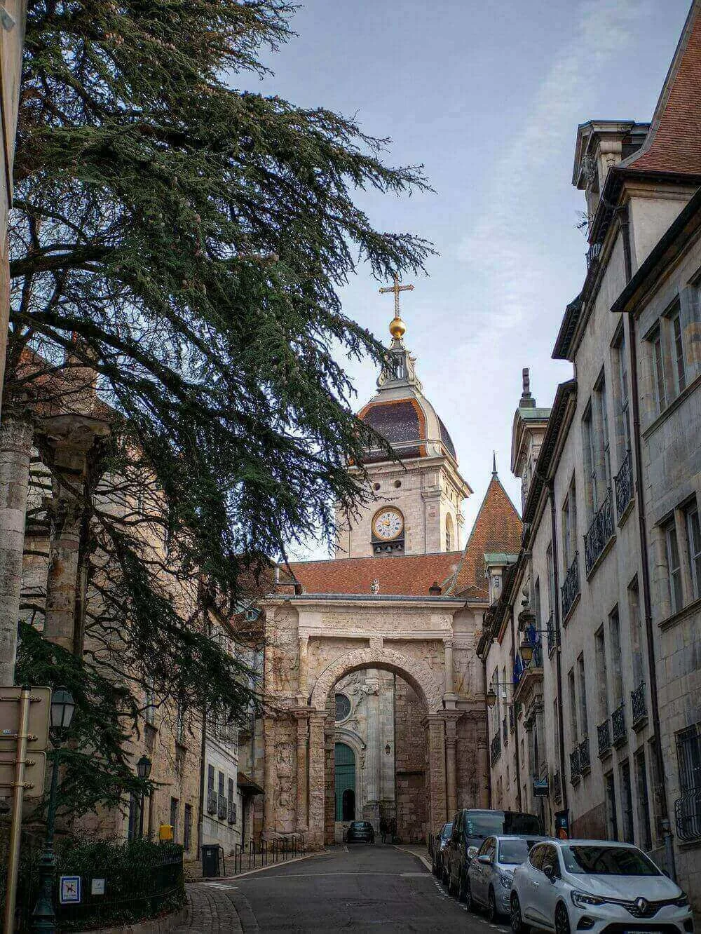 Vue d’une rue pittoresque à Besançon, bordée de bâtiments historiques et menant vers l’Église Saint-Vincent. Idéal pour découvrir notre agence et ses services d’essayage dans cette ville riche en architecture et culture.
