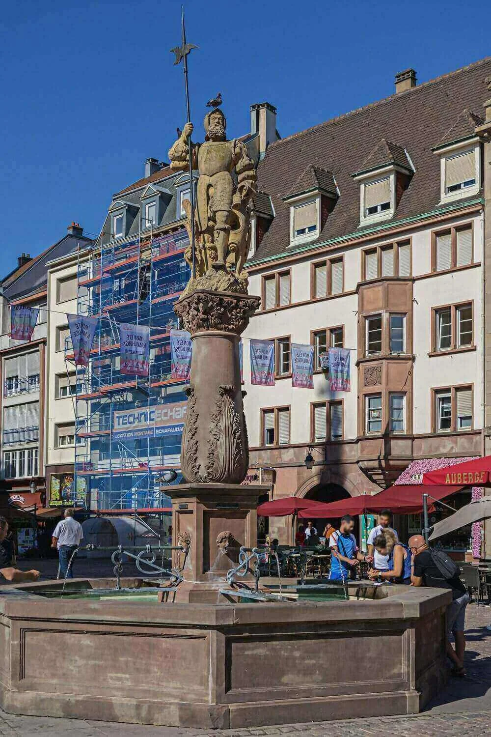 Vue d’une fontaine historique avec une statue, idéale pour découvrir comment devenir mannequin d’essayage à Mulhouse.