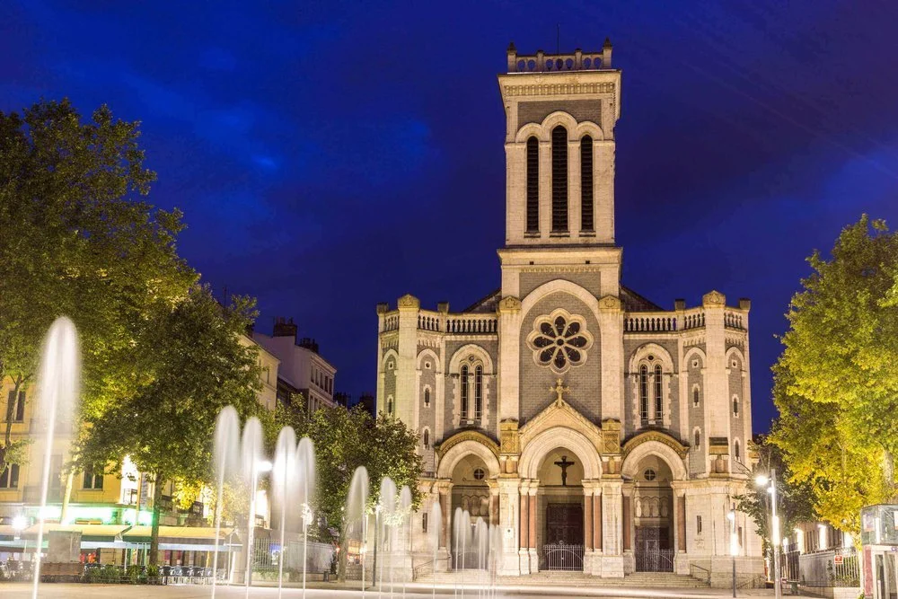 Vue nocturne de la cathédrale Saint-Étienne, illuminée et entourée de fontaines, reflétant l’architecture historique et la dynamique de la ville. Idéal pour découvrir notre agence et ses services d’essayage dans cette destination culturelle.