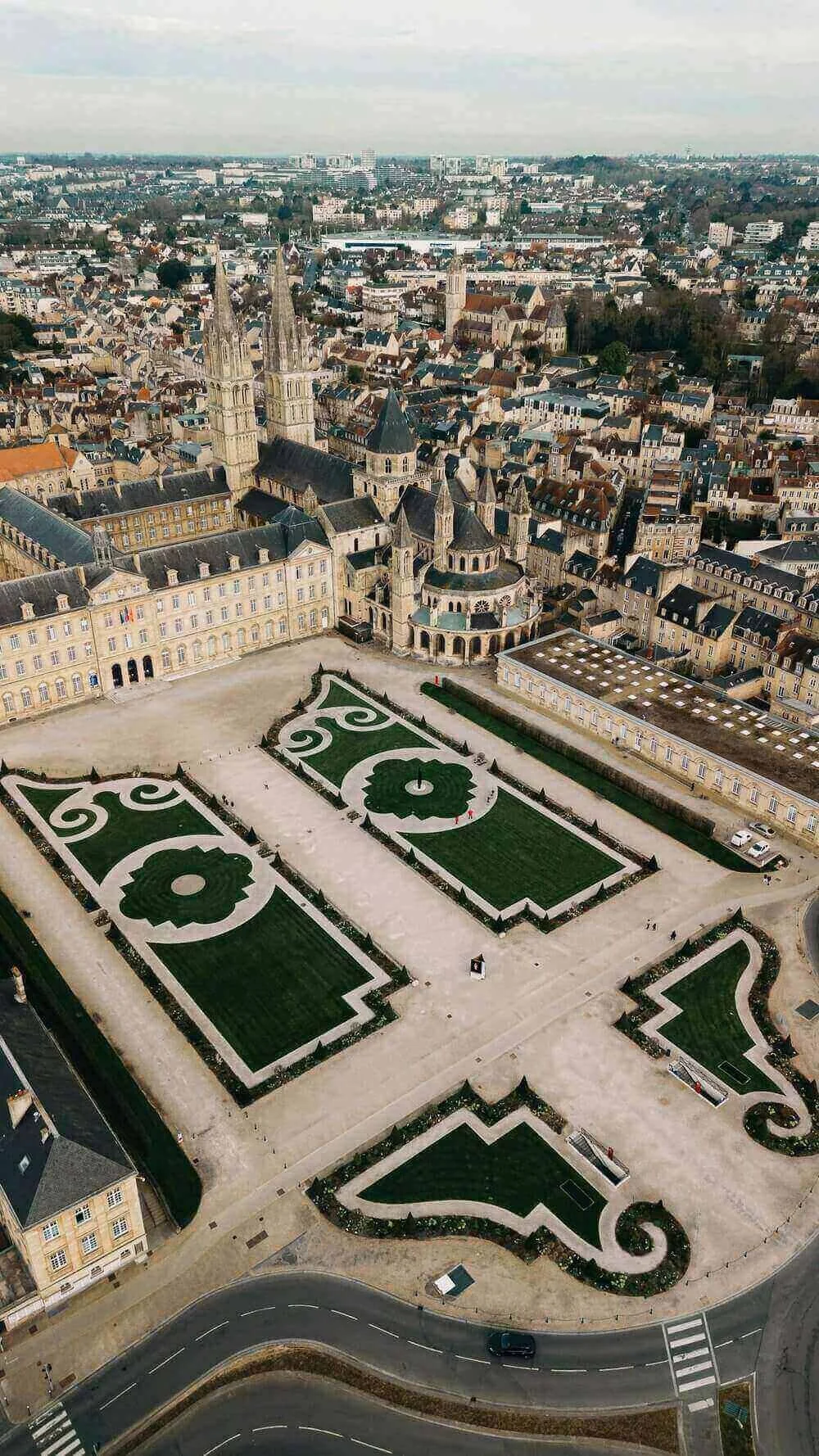 Vue aérienne de Caen, mettant en avant les jardins ornés et les bâtiments historiques, notamment la cathédrale et le château. Idéal pour découvrir comment devenir mannequin d’essayage à Caen, une ville riche en patrimoine culturel et architectural.
