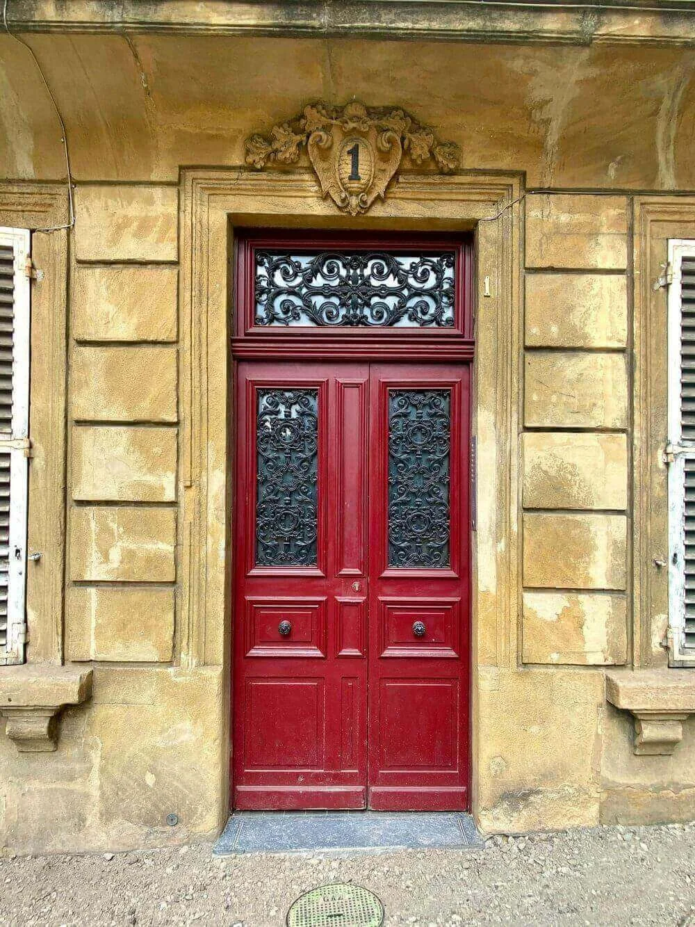Vue d'une porte historique à Metz, avec des détails architecturaux élégants et une couleur rouge vif. Idéal pour découvrir comment devenir mannequin d’essayage à Metz, une ville riche en patrimoine culturel et architectural.
