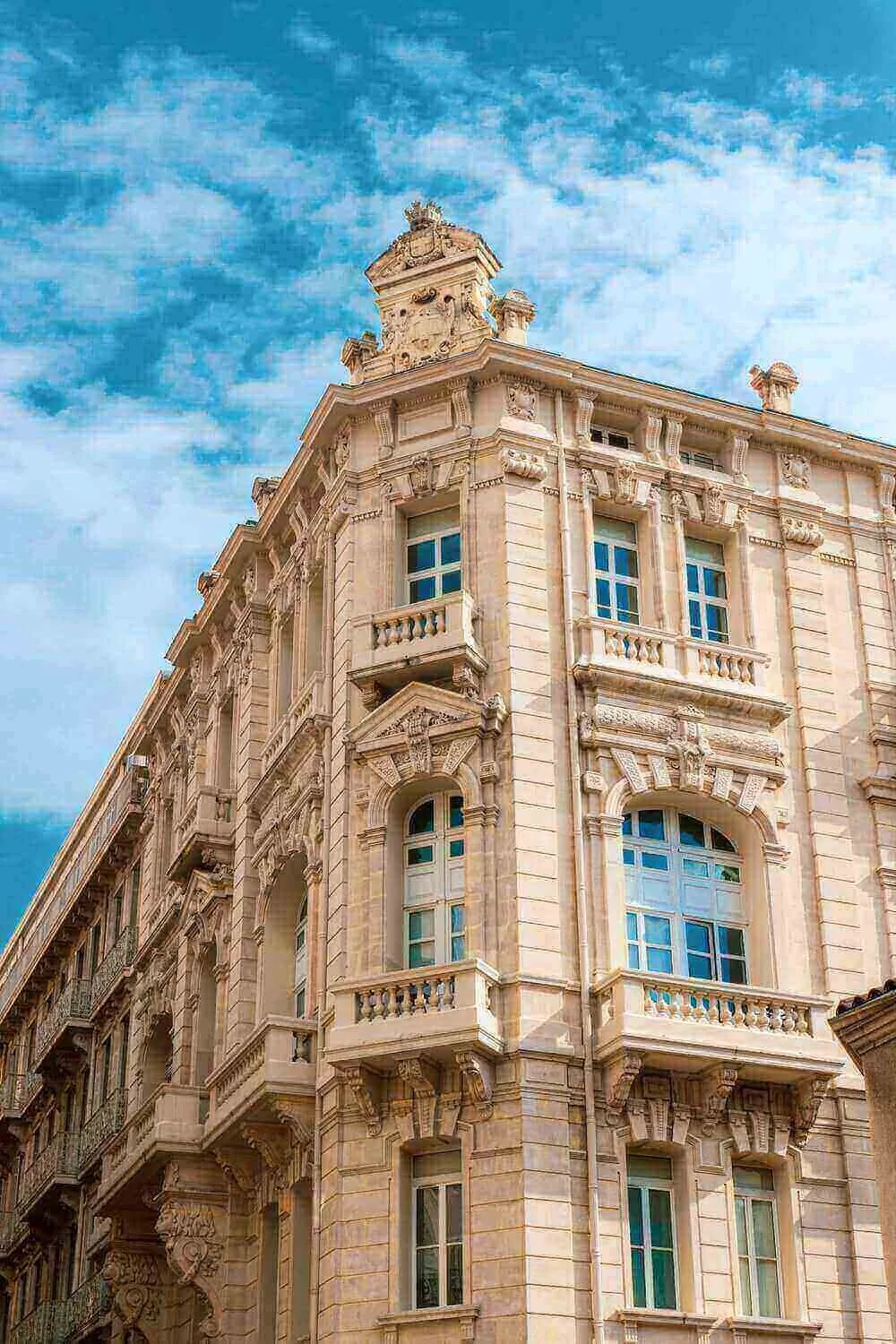 Vue d’un bâtiment historique à Toulon, avec des détails architecturaux élégants et un ciel bleu en arrière-plan. Idéal pour découvrir comment devenir mannequin d’essayage à Toulon, une ville où l’histoire et la modernité coexistent harmonieusement.