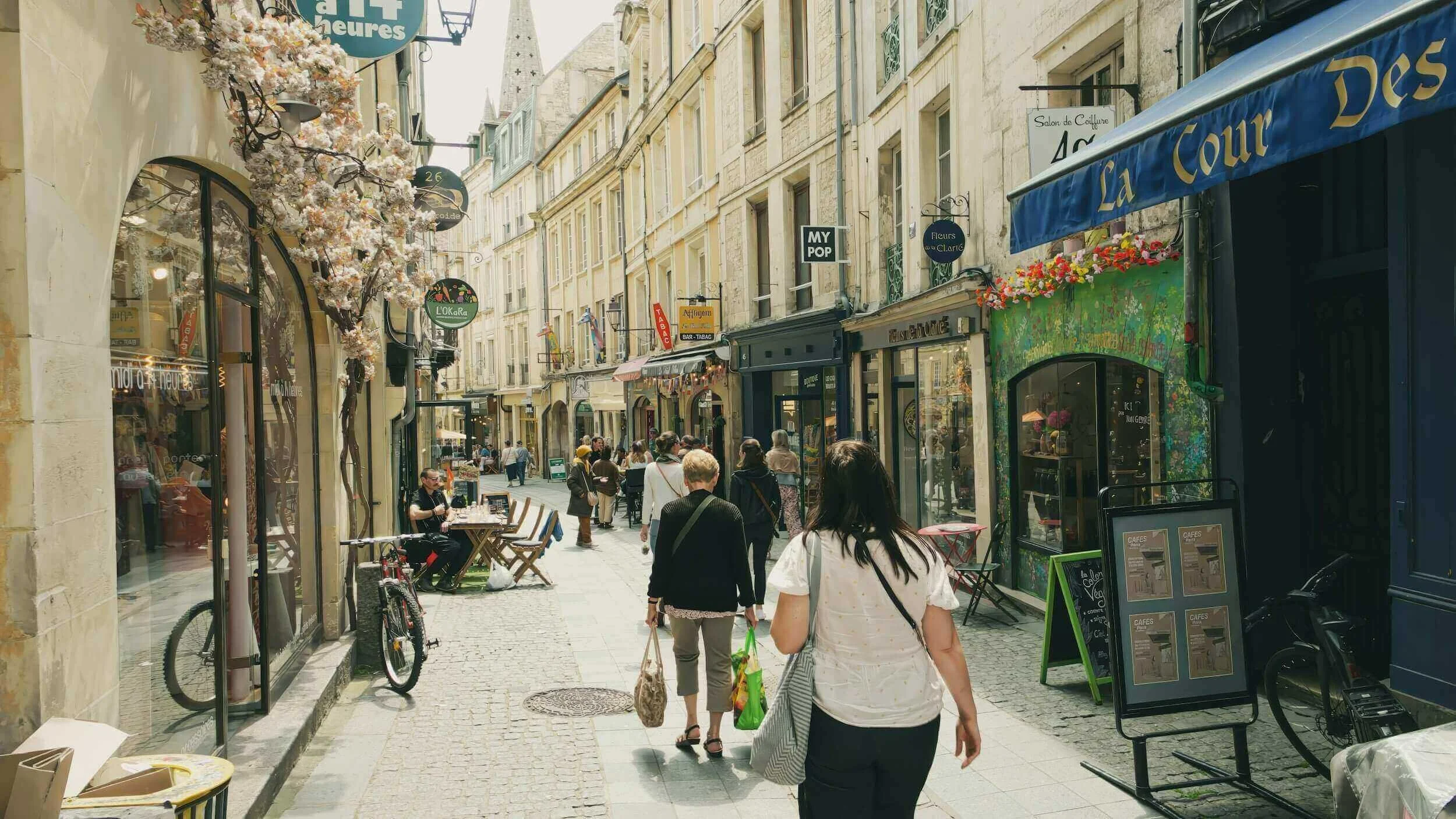 Vue d’une rue animée à Caen, bordée de boutiques colorées et de terrasses accueillantes. Idéal pour découvrir notre agence et ses services d’essayage dans cette ville dynamique et chaleureuse.