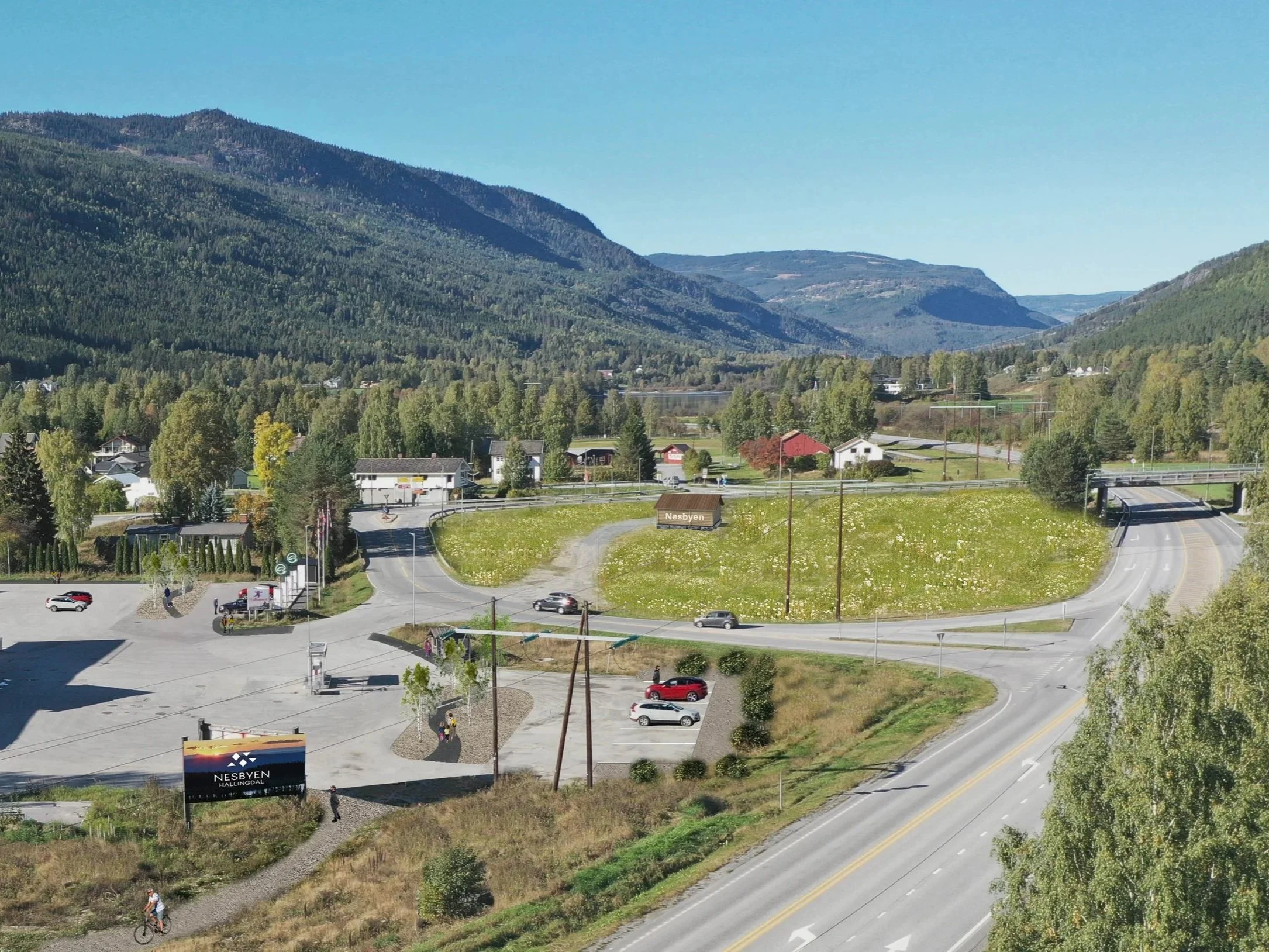 Bilde av en landsby med veikryss, biler, hus og fjell i bakgrunnen.